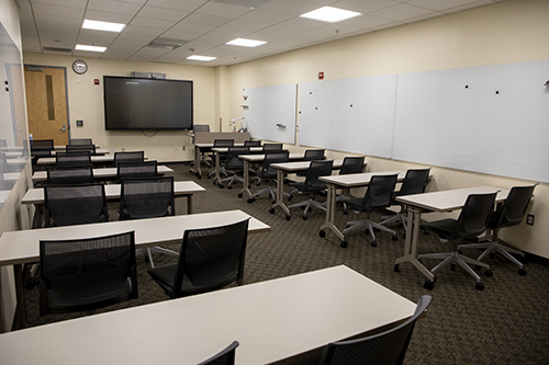 Photo of Doyle 141 - desks, a large screen, and white boards