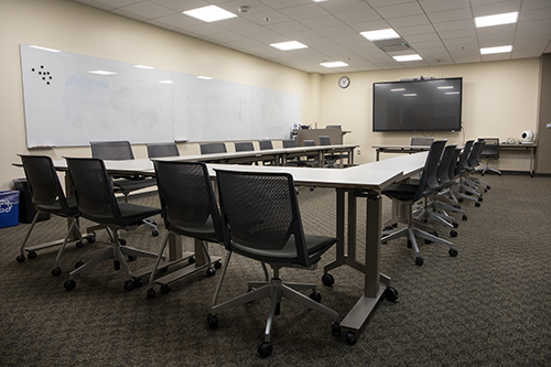 Photo of Doyle 141 - half circle of desks, large screen, whiteboards
